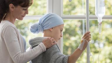 Mother comforts child with cancer receiving IV treatment 