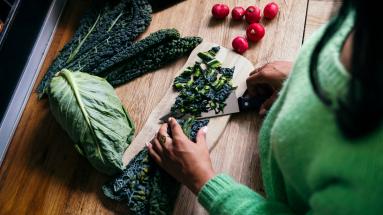 woman cutting vegetables on wooden cutting board 