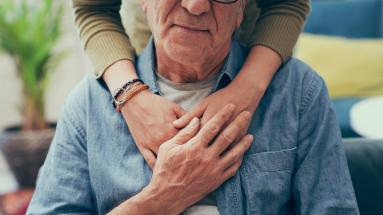 arms gracefully wrapped around a man sitting down