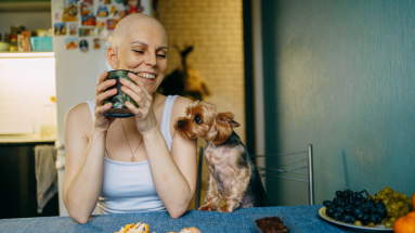 woman sitting at table with puppy smiling