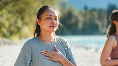 a woman on the sand with hand against her chest 