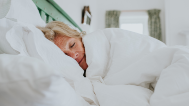 Woman sleeping in bed under white comforter