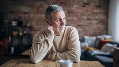 man with chin wresting on hand on table 