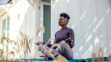 woman sitting outside criss cross apple sauce on yoga mat meditating