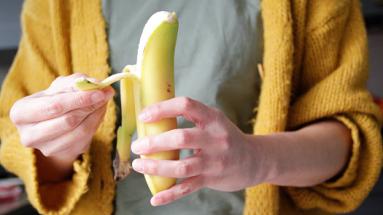 person in yellow sweater peeling a banana