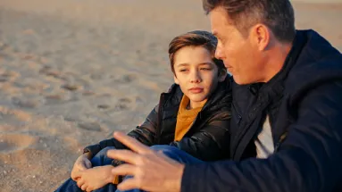 father and son sitting on the sand during the spring