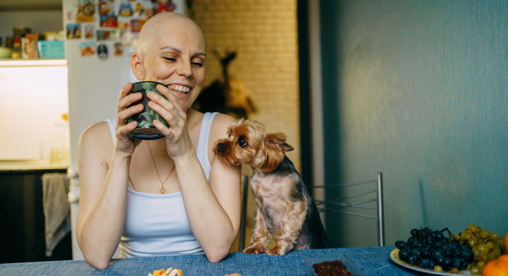 woman sitting at table with puppy smiling