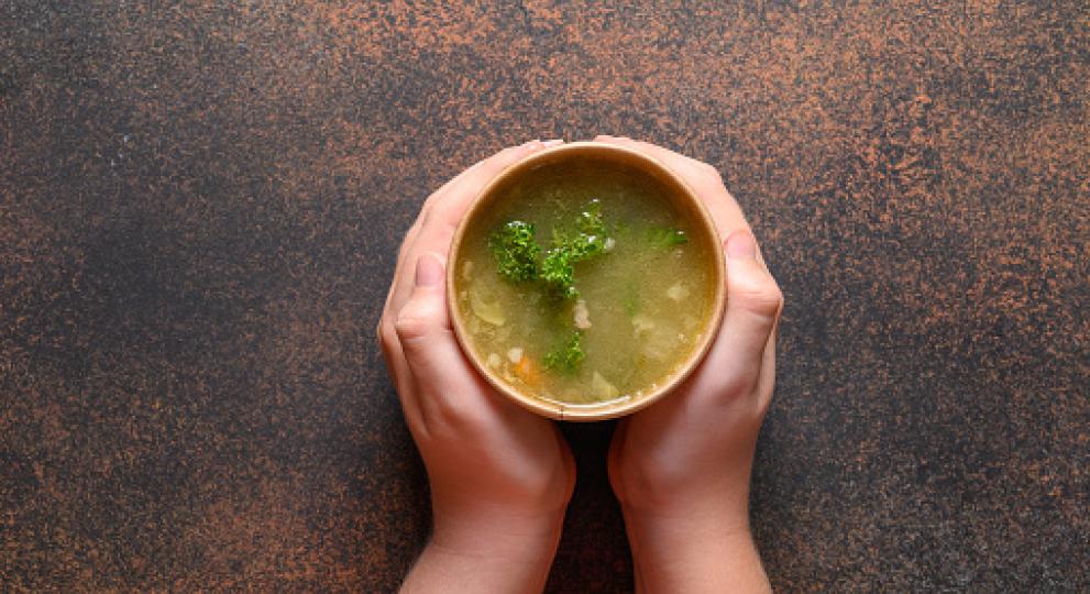 hands holding a cup of soup on both sides 