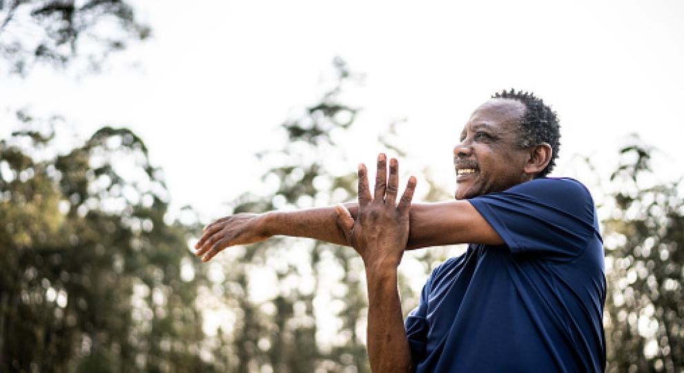 Man stretching his left arm over his right arm